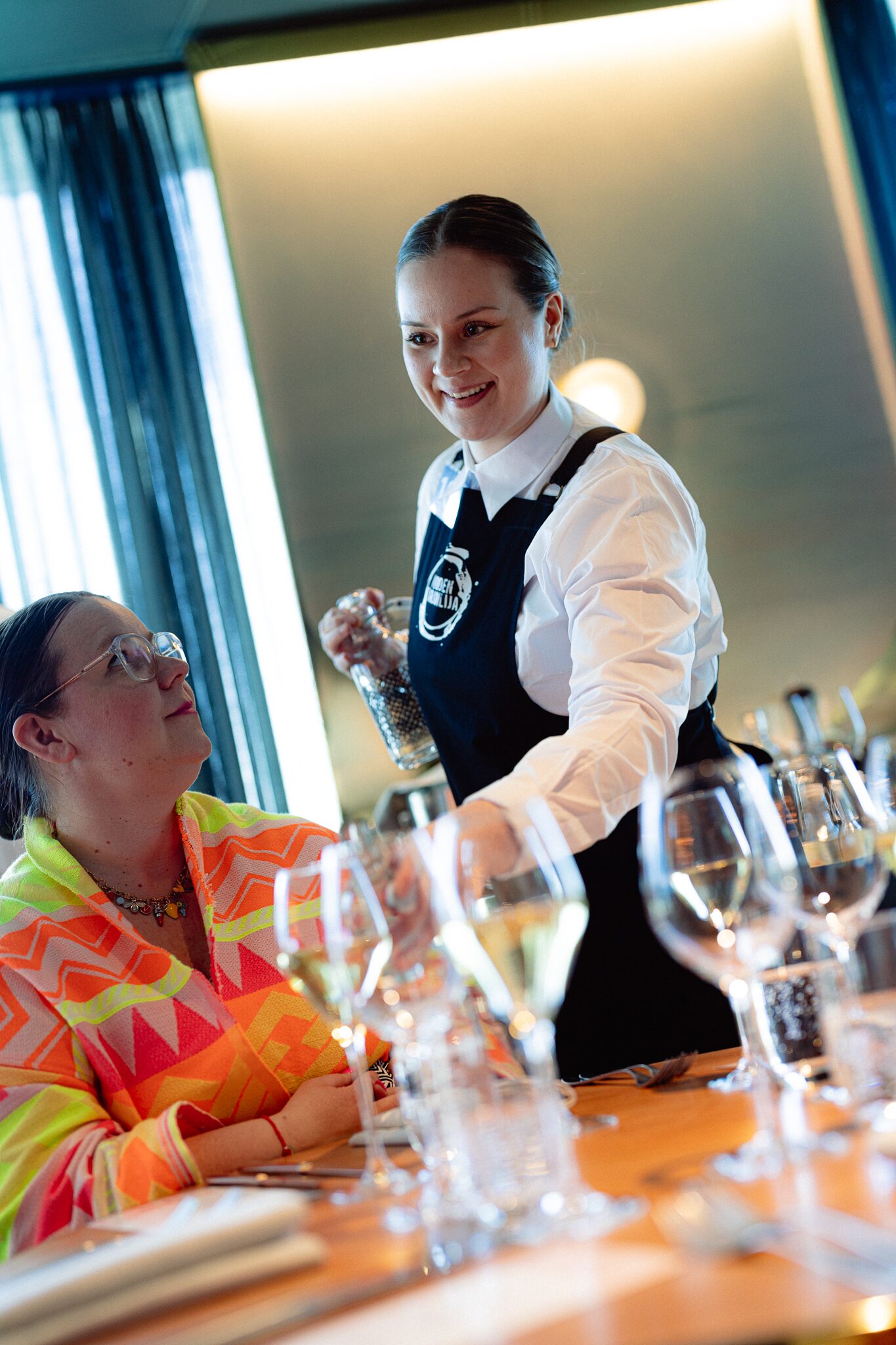 Tarjoilija kattaa pöytää ravintolasalissa